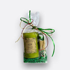 Green candle in clear packaging with decorative ribbons on a white background