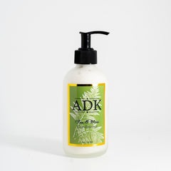Bottle of ADK hair product with a green label on a white background