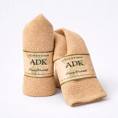 Two beige washcloths with ADK branding on a white background