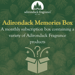 Adirondack Fragrance Adirondack Memories Box advertisement with green background and pine cone pattern.