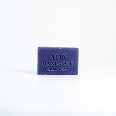 Purple bar of soap with 'ADK Handmade' branding on a white background