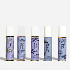 Five rollerball bottles with purple labels featuring botanical illustrations on a white background.