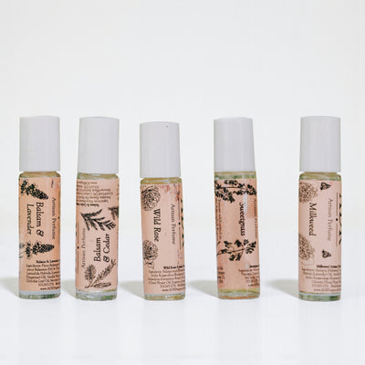 Five small bottles of essential oils with labels on a white background