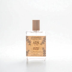 Clear glass room spray bottle with wooden cap and 'ADK' label on a white background