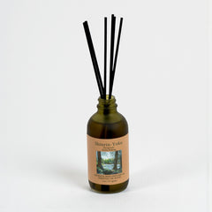 A bottle of Shinrin-Yoku diffuser with black sticks on a white background