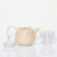 White ceramic teapot and clear glass cup on a white background