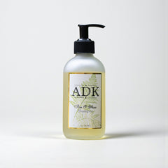 Bottle of ADK shampoo with a pump on a white background